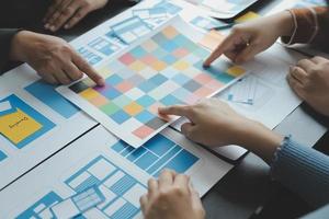 Close up ux developer and ui designer brainstorming about mobile app interface wireframe design on table with customer breif and color code at modern office.Creative digital development agency photo