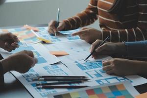 Close up ux developer and ui designer brainstorming about mobile app interface wireframe design on table with customer breif and color code at modern office.Creative digital development agency photo