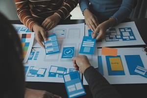 Close up ux developer and ui designer brainstorming about mobile app interface wireframe design on table with customer breif and color code at modern office.Creative digital development agency photo