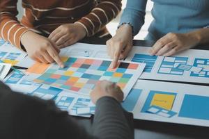 Close up ux developer and ui designer brainstorming about mobile app interface wireframe design on table with customer breif and color code at modern office.Creative digital development agency photo