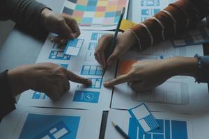 Close up ux developer and ui designer brainstorming about mobile app interface wireframe design on table with customer breif and color code at modern office.Creative digital development agency photo