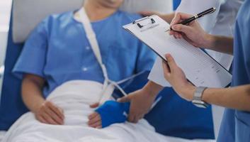 Man with broken arm in cast lying on bed in hospital. The emergency center treatment is plaster and hangs with sling for a further cure in an orthopedic clinic. Patient pain from accident injury. photo