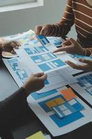 Close up ux developer and ui designer brainstorming about mobile app interface wireframe design on table with customer breif and color code at modern office.Creative digital development agency photo