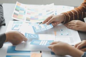 Close up ux developer and ui designer brainstorming about mobile app interface wireframe design on table with customer breif and color code at modern office.Creative digital development agency photo