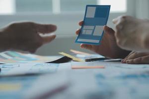 Close up ux developer and ui designer brainstorming about mobile app interface wireframe design on table with customer breif and color code at modern office.Creative digital development agency photo