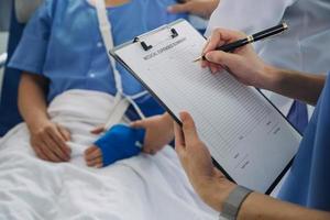 Man with broken arm in cast lying on bed in hospital. The emergency center treatment is plaster and hangs with sling for a further cure in an orthopedic clinic. Patient pain from accident injury. photo