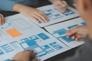 Close up ux developer and ui designer brainstorming about mobile app interface wireframe design on table with customer breif and color code at modern office.Creative digital development agency photo