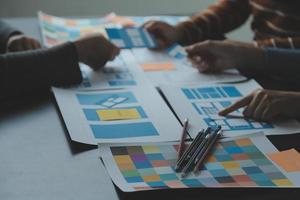 Close up ux developer and ui designer brainstorming about mobile app interface wireframe design on table with customer breif and color code at modern office.Creative digital development agency photo