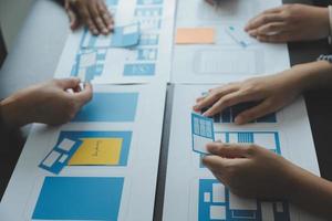 Close up ux developer and ui designer brainstorming about mobile app interface wireframe design on table with customer breif and color code at modern office.Creative digital development agency photo