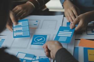 Close up ux developer and ui designer brainstorming about mobile app interface wireframe design on table with customer breif and color code at modern office.Creative digital development agency photo