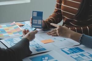Close up ux developer and ui designer brainstorming about mobile app interface wireframe design on table with customer breif and color code at modern office.Creative digital development agency photo