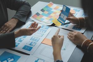 Close up ux developer and ui designer brainstorming about mobile app interface wireframe design on table with customer breif and color code at modern office.Creative digital development agency photo
