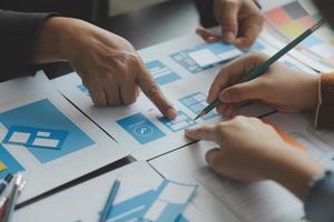 Close up ux developer and ui designer brainstorming about mobile app interface wireframe design on table with customer breif and color code at modern office.Creative digital development agency photo