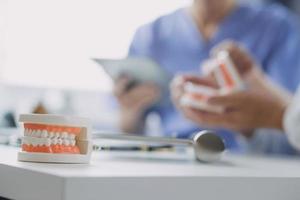 Male dentist with plastic jaw model on light background photo