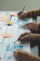 Close up ux developer and ui designer brainstorming about mobile app interface wireframe design on table with customer breif and color code at modern office.Creative digital development agency photo