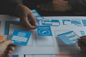 Close up ux developer and ui designer brainstorming about mobile app interface wireframe design on table with customer breif and color code at modern office.Creative digital development agency photo