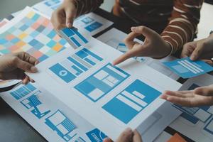 Close up ux developer and ui designer brainstorming about mobile app interface wireframe design on table with customer breif and color code at modern office.Creative digital development agency photo