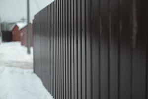 Fence in winter. Solid fence made of prof sheet. Steel brown prof sheet. photo