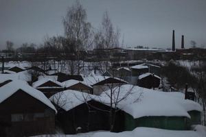 Overcast landscape in winter. Snow on roofs. Pipes on horizon. photo