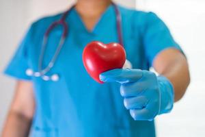 Doctor holding a red heart in hospital ward, healthy strong medical concept. photo