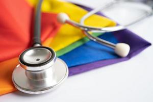 Black stethoscope on rainbow flag background, symbol of LGBT pride month celebrate annual in June social, symbol of gay, lesbian, bisexual, transgender, human rights and peace. photo