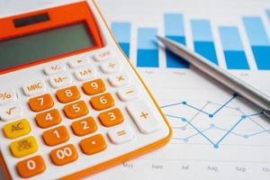 Pen and calculator on chart or graph paper. Financial, account, statistics and business data concept. photo