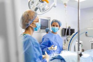 Female surgeon with surgical mask at operating room. Young woman doctor in surgical uniform in hospital operation theater. photo