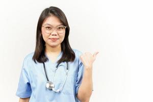 demostración y señalando producto con pulgar de asiático joven médico aislado en blanco antecedentes foto