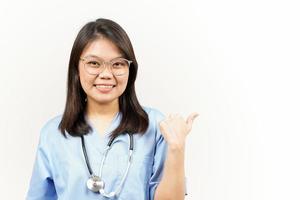 demostración y señalando producto con pulgar de asiático joven médico aislado en blanco antecedentes foto