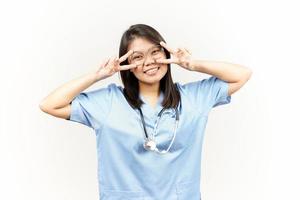 Showing Peace Sign Of Asian Young Doctor Isolated On White Background photo