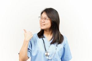 demostración y señalando producto con pulgar de asiático joven médico aislado en blanco antecedentes foto