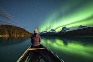 viajero mujer sentado en canoa con Aurora borealis terminado espíritu isla en maligno lago a jaspe nacional parque, alberta, Canadá foto