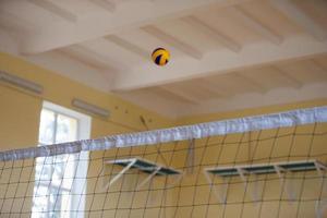 un vóleibol pelota moscas terminado el neto. vóleibol en el gimnasia. foto