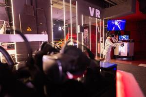 Boy kid playing game using virtual reality headset and gamepads in playing club. photo