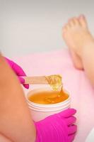 Cosmetologists waxing the female legs photo