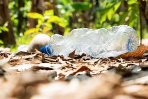 Plastic bottles and trash left in summer forest after picnic. Natural pollution. Ecology problem concept. photo