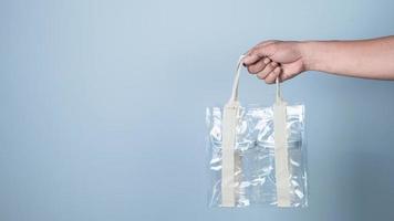 Hand holding plastic bag on blue background, Recycling concept. photo