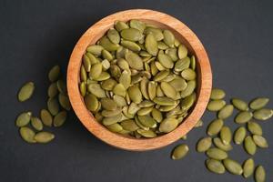 Pumpkin seeds in a wooden bowl on a dark background photo