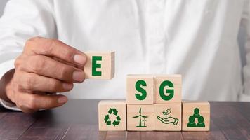 ESG concept of governance and social environment. Sustainable company development. Hand holding wooden cube with letter E icon photo