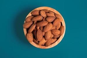 Almonds in wooden bowl on blue background photo