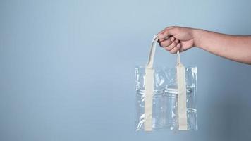 Hand holding plastic bag on blue background, Recycling concept. photo