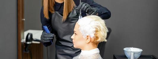 Hairdressers dyeing hair of woman photo