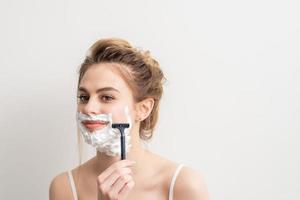 Woman shaving face with razor photo