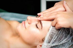 Female therapist making forehead massage photo