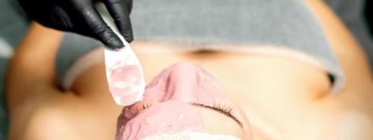 Cosmetologist applying an alginic mask photo