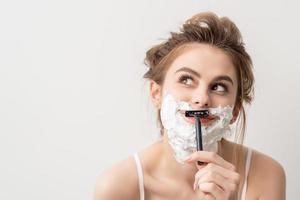 Woman shaving face with razor photo