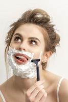 mujer afeitado cara con maquinilla de afeitar foto