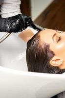 Hairdresser washing hair of client photo