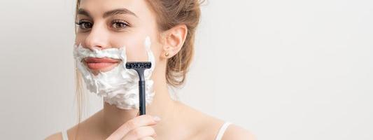 Woman shaving face with razor photo