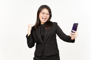 Celebration and Holding Smartphone Of Beautiful Asian Woman Wearing Black Blazer Isolated On White photo